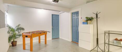 A spacious room with a foosball table, a coat rack, and a potted plant.