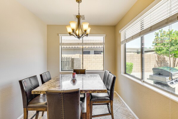 A dining area with a marble table, leather chairs, and a chandelier.