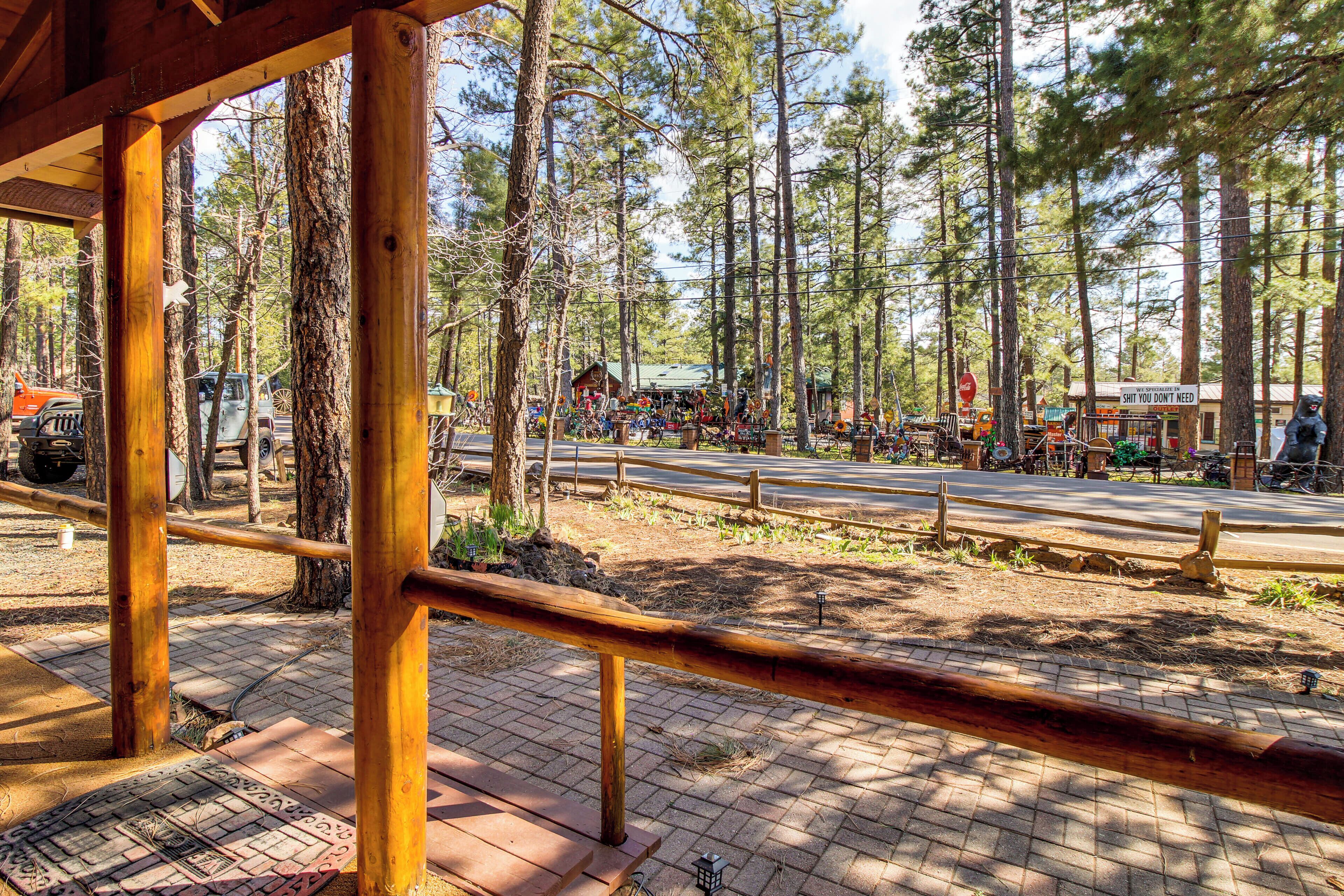 Une structure en bois avec un chemin pavé, entourée de grands pins.