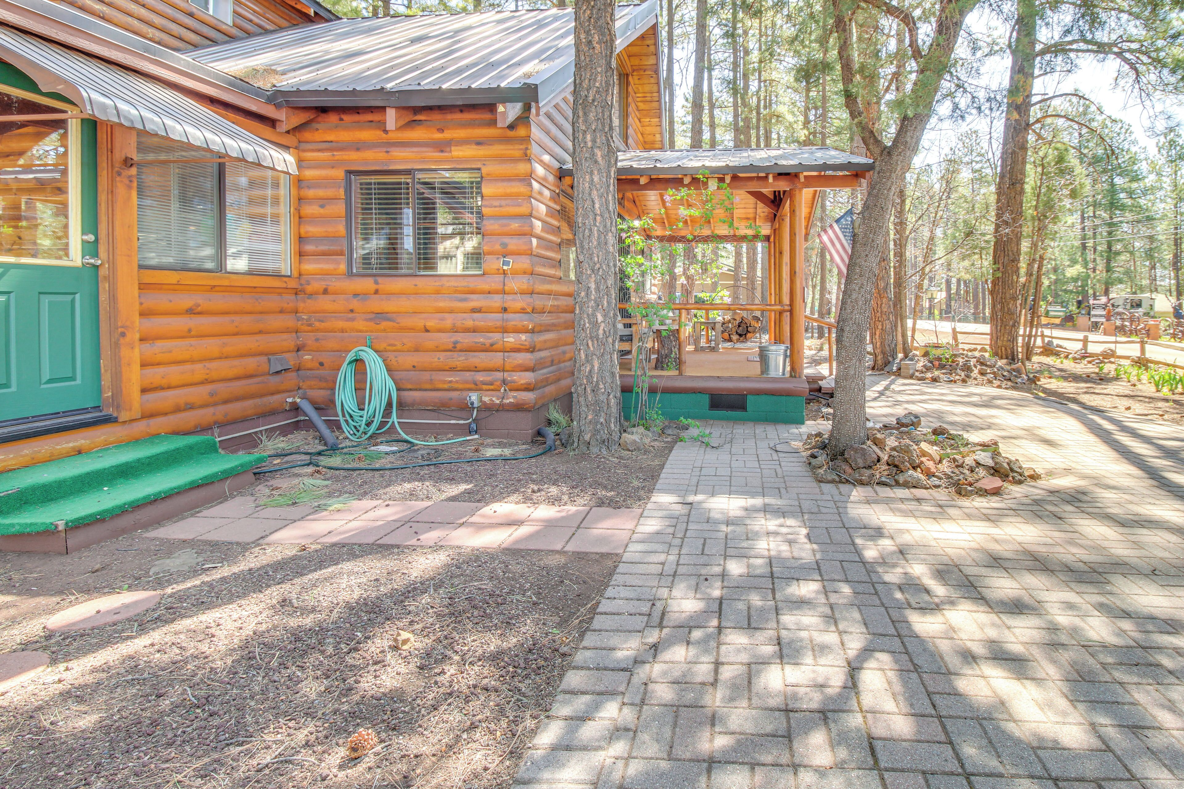 A log cabin with a green door, a covered porch, and a paved walkway.