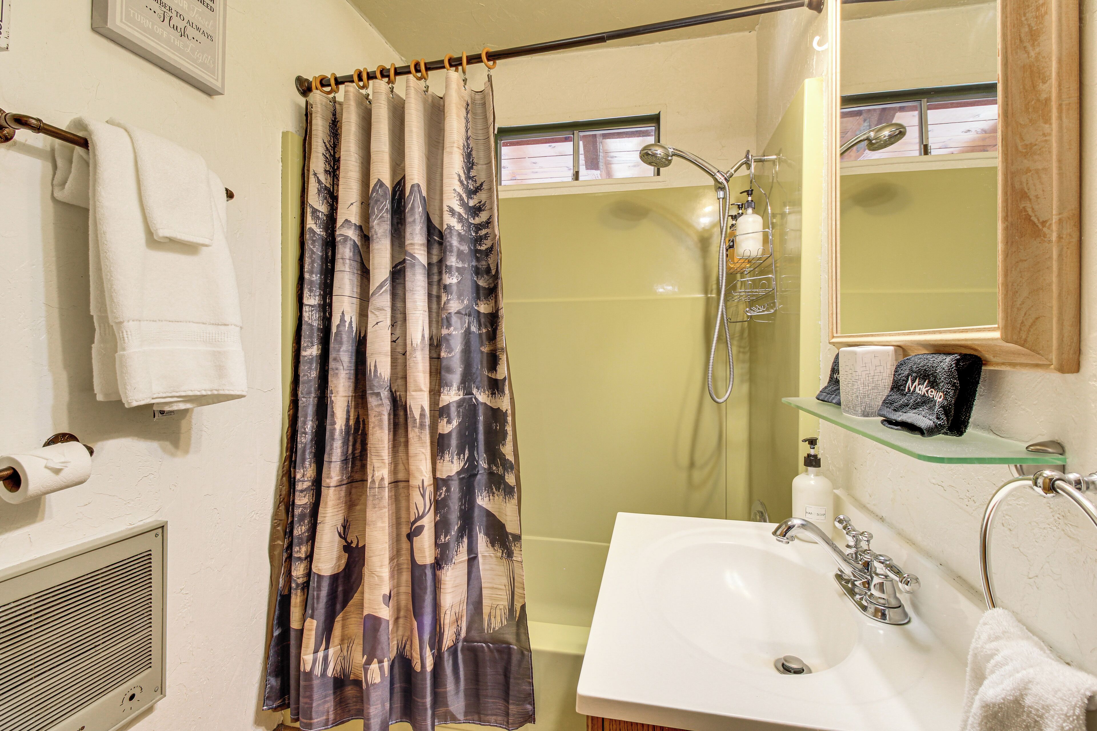 A bathroom with a shower, a sink, a mirror, and a towel rack.
