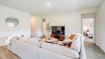 Ein modernes Wohnzimmer mit einer großen Couch, einem Couchtisch und einem Flachbildfernseher.