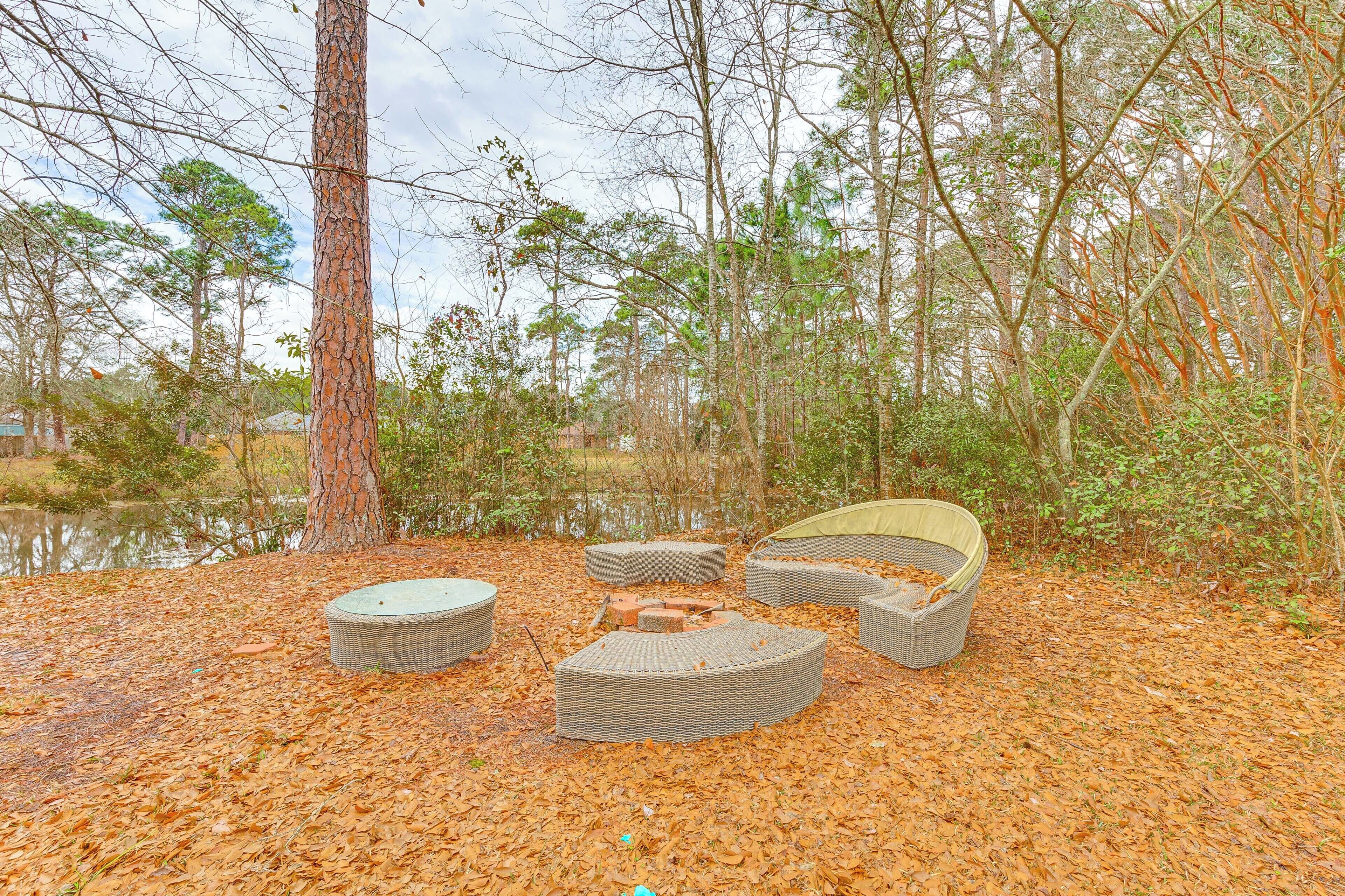 A circular outdoor seating area with a bench and cushions, surrounded by trees and a body of water.