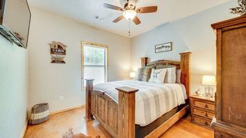A bedroom with a wooden bed, a nightstand, a lamp, a ceiling fan, and a window with blinds.