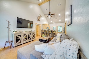 A spacious living room with a large gray sectional sofa, a wooden entertainment center, and a mounted television.