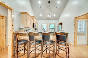 A kitchen with wooden cabinets, a central island with bar stools, and a hanging light fixture.