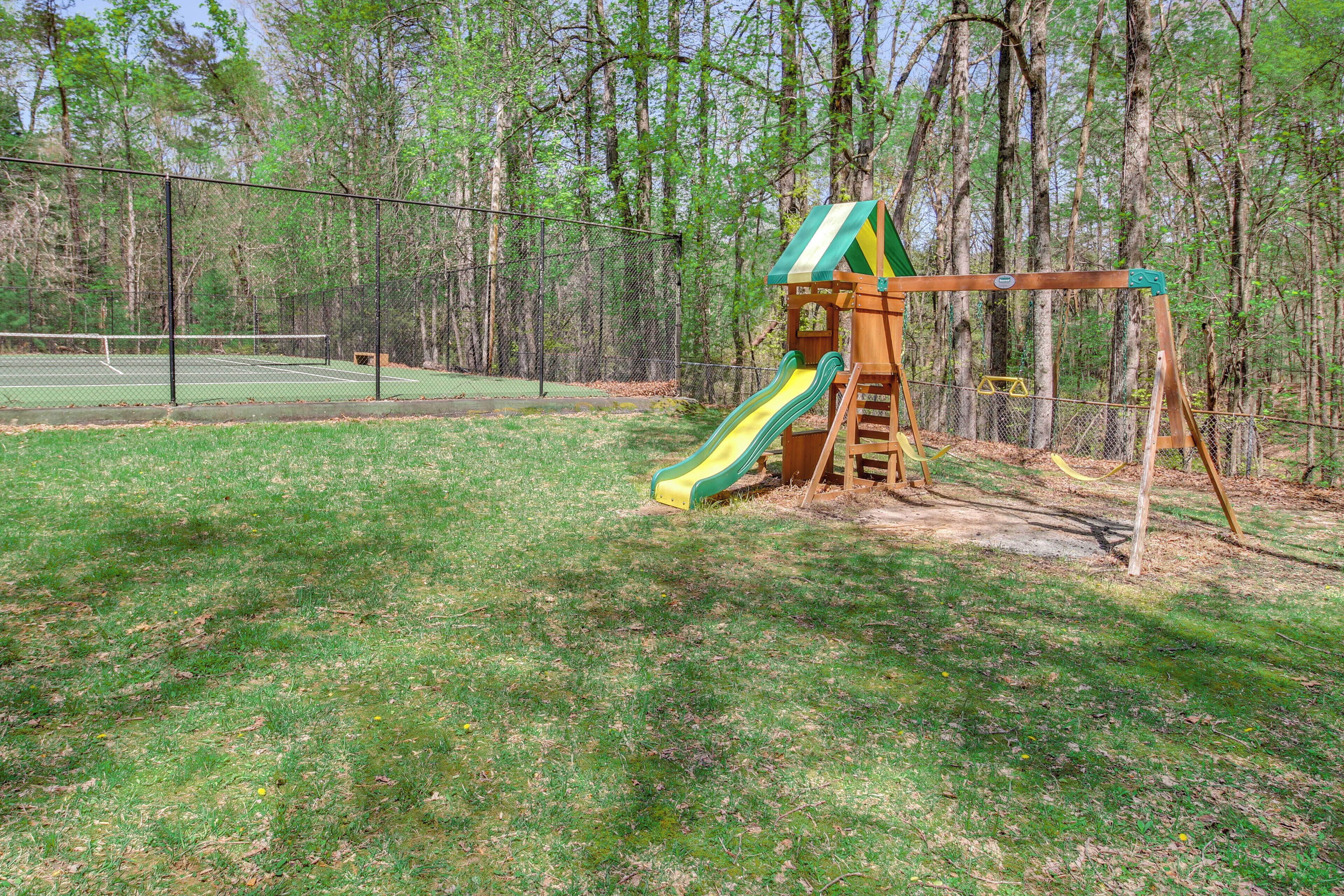 Ein Spielplatz mit Rutsche und Schaukel inmitten eines bewaldeten Gebiets.