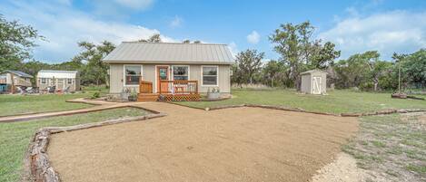 A single-story house with a front porch, a fenced yard, and a small shed.