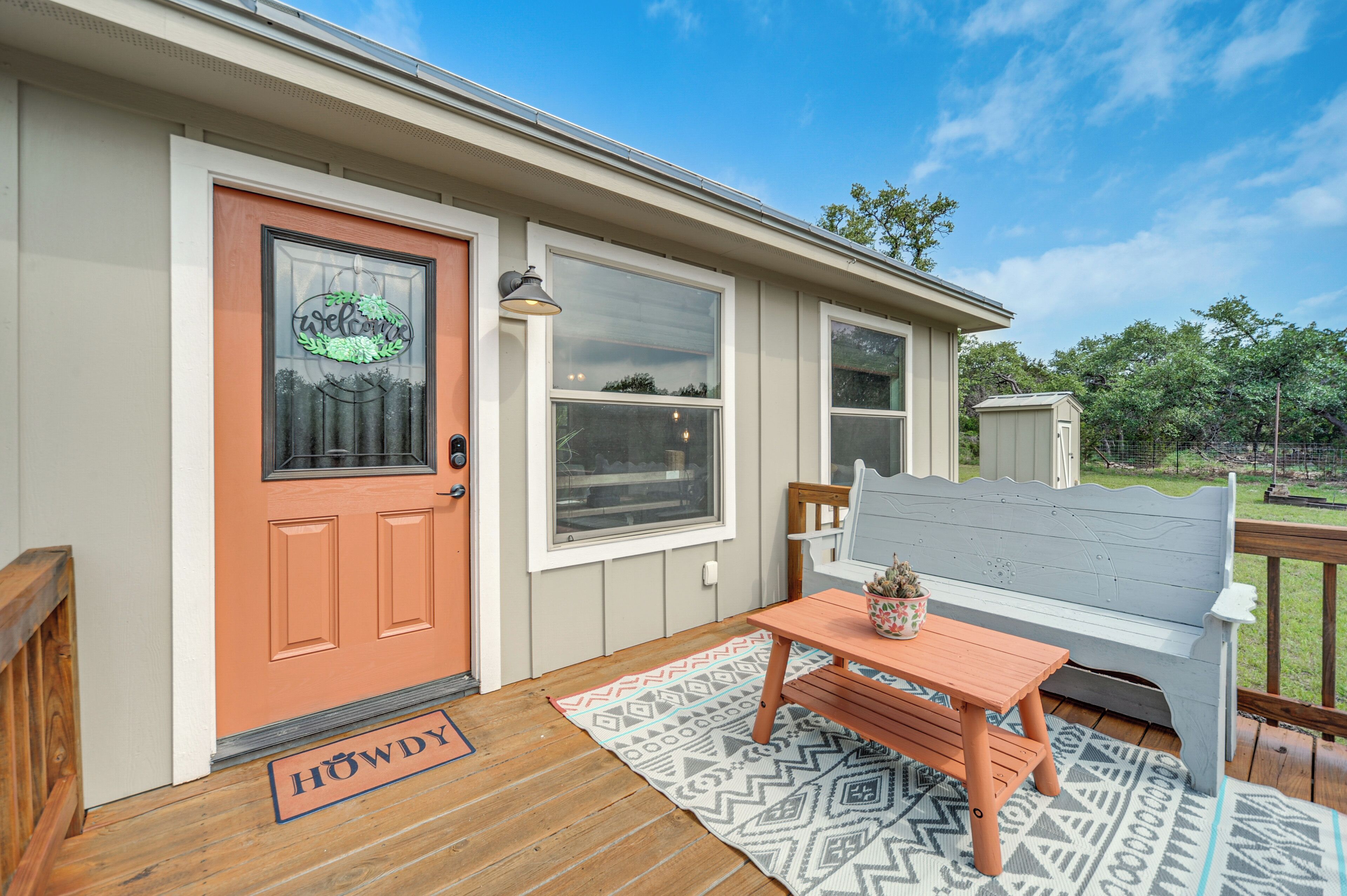 A house with a red door, a bench, and a table on the porch.