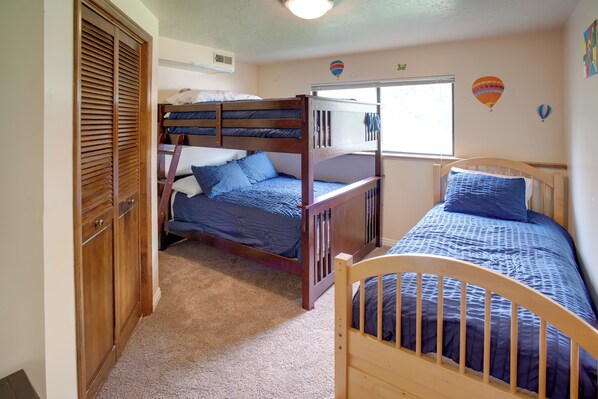 A bedroom with bunk beds, a wooden wardrobe, and a window with a view. - Hike, Golf, Ski & More: Family Home in South Weber (Ogden)