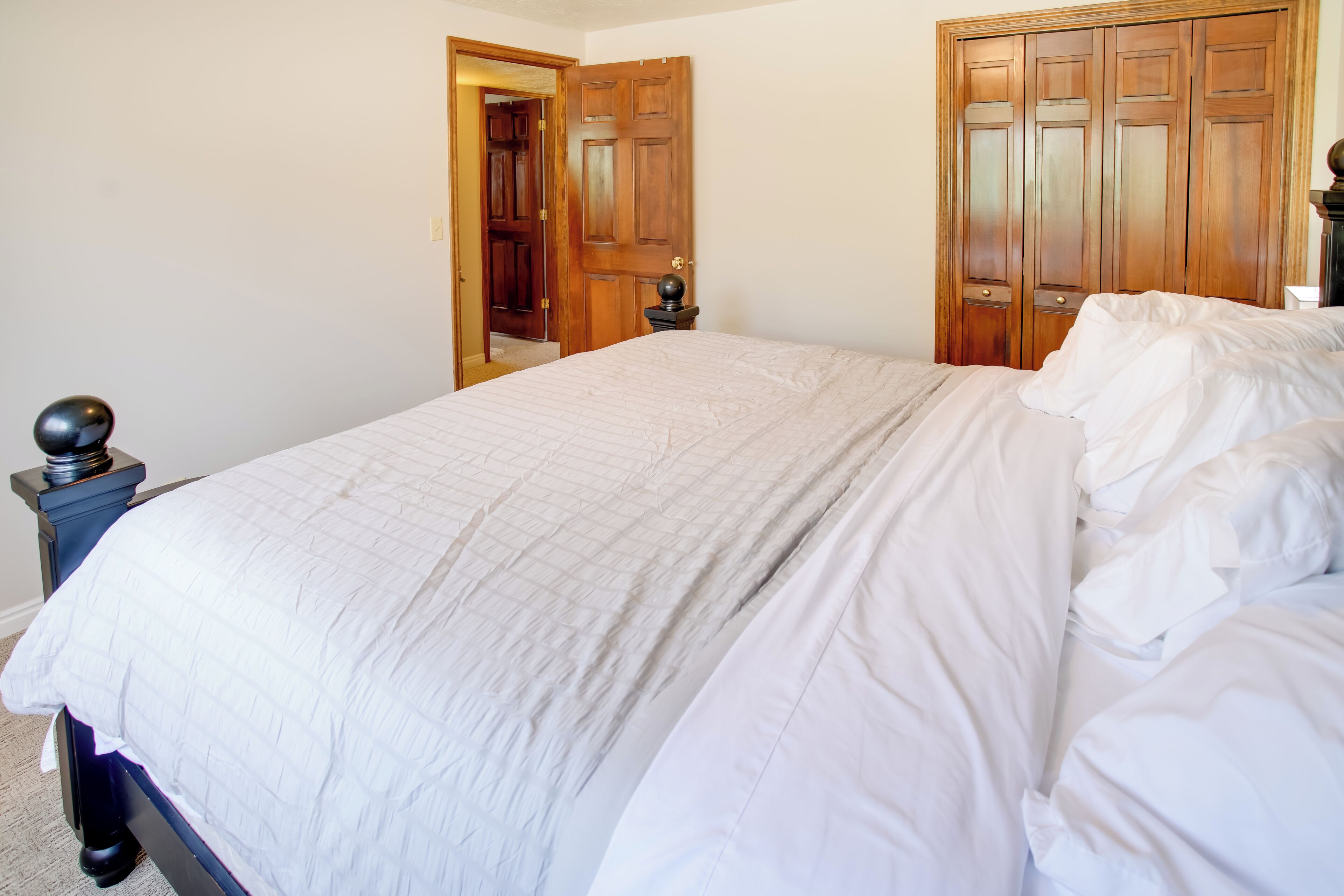 Una camera da letto con un letto grande, un armadio in legno e un tavolino con una lampada.