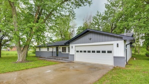 Une maison de plain-pied avec un garage, une véranda et une allée.