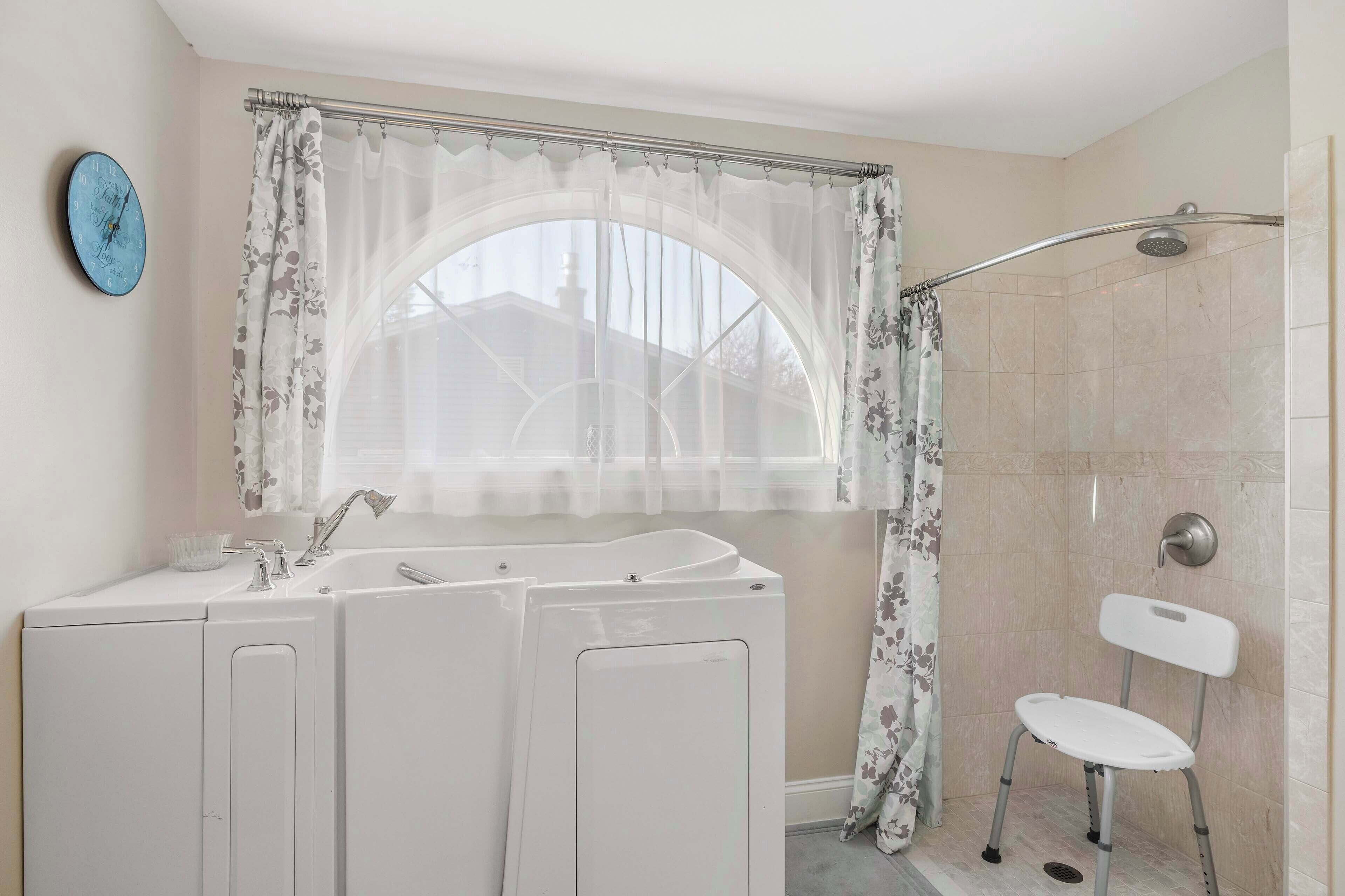 A bathroom with a shower, a sink, and a chair.