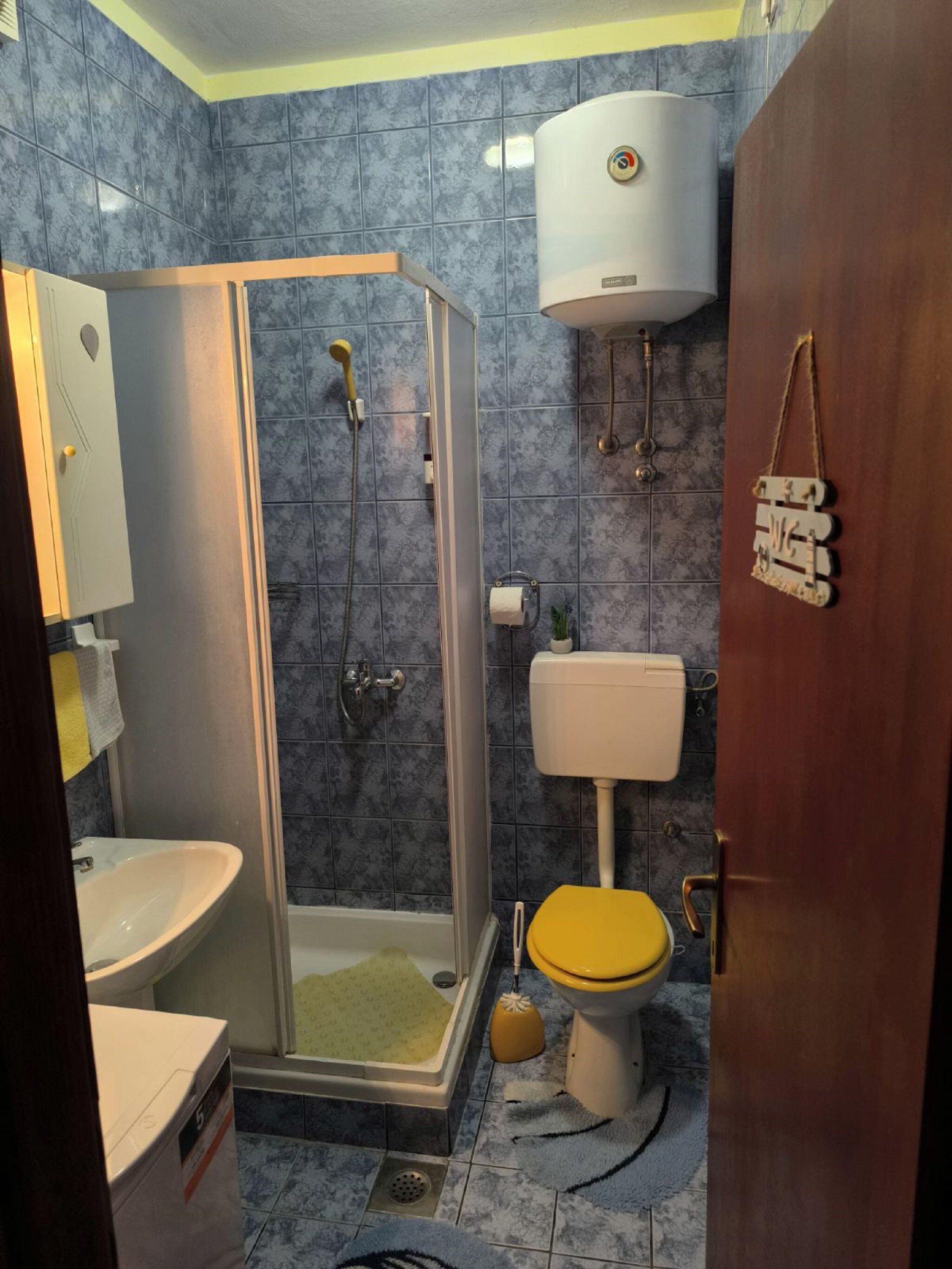 A bathroom with a glass-enclosed shower, a toilet, and a sink.