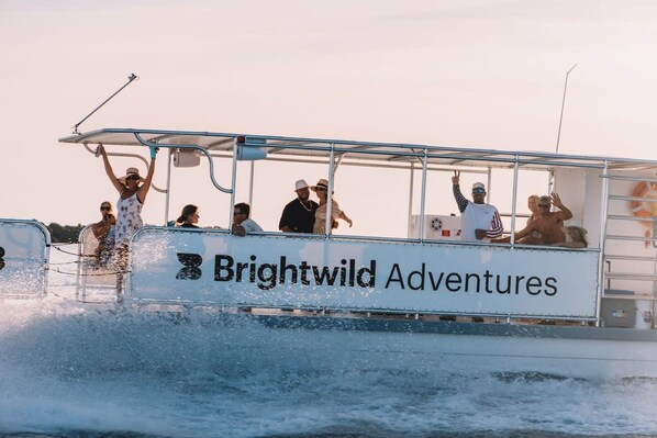 A boat with passengers, branded "Brightwild Adventures," on a body of water.