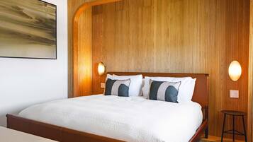 A hotel room with a large bed, wooden headboard, two wall-mounted lights, and a painting on the wall.