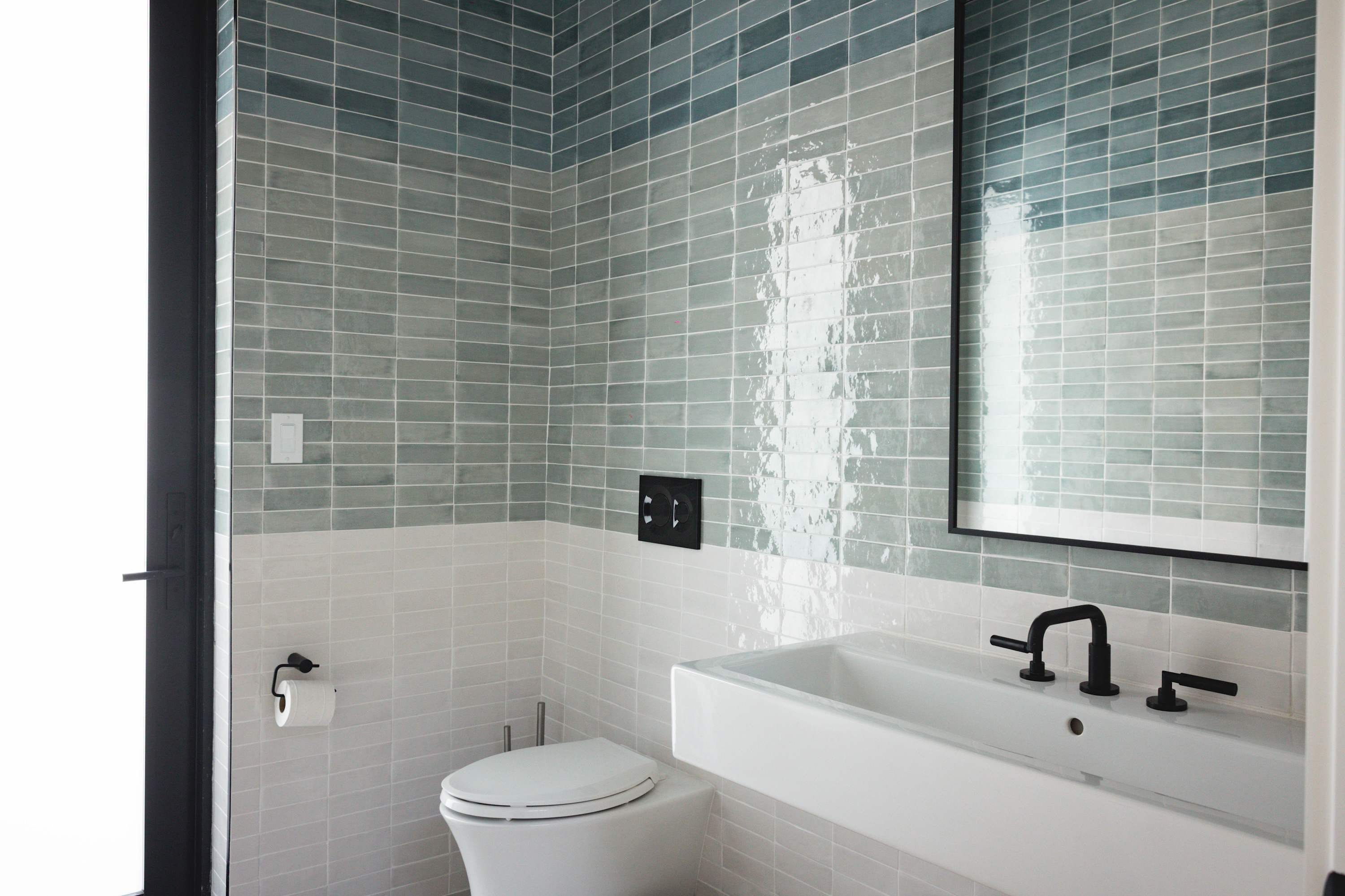 A bathroom with a white toilet, a white sink with a black faucet, and a mirror above the sink.