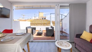 Um apartamento moderno com varanda, mobiliado com sofá, cadeiras e mesa de jantar.