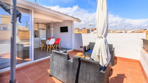 Terraço no telhado com mobiliário de exterior, área de refeições e televisão.