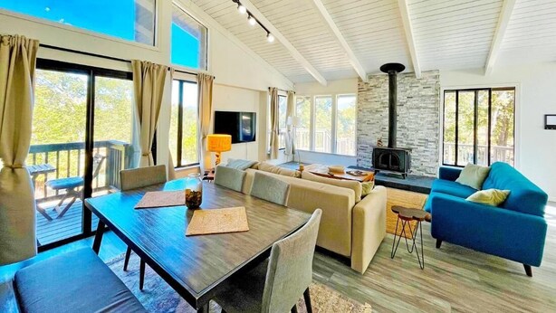 A spacious living area with a dining table, sofas, and a stone fireplace. - Modern Yosemite Cabin, 15min Bass Lake, Sleeps 8 (Oakhurst)