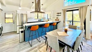 A modern kitchen with a central island, bar stools, and a dining table with chairs. - Modern Yosemite Cabin, 15min Bass Lake, Sleeps 8 (Oakhurst)