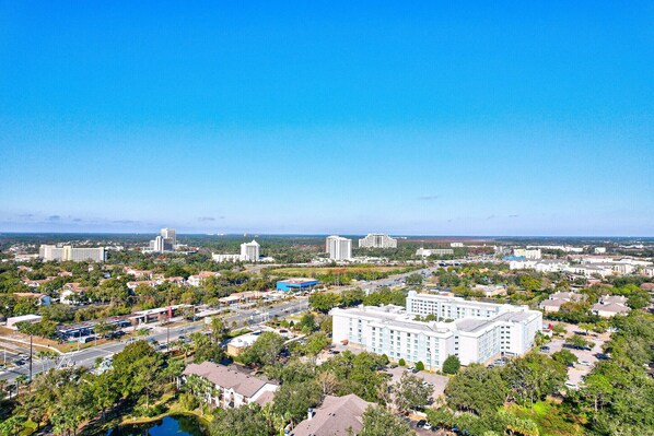 A cityscape with a large hotel, a highway, and surrounding greenery. - Charming 1-bedroom condo on Lake Bryan, Disney Fireworks. 10 mins to Disney! (Orlando)