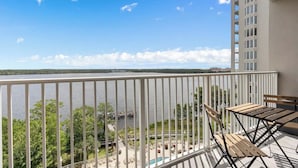 Ein Balkon mit Seeblick, Holzmöbeln und einem Poolbereich.
