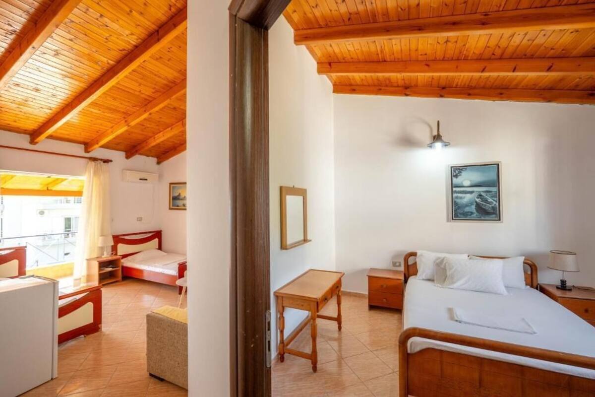 Une chambre d’hôtel avec un plafond en bois, un lit, un bureau, une chaise et une fenêtre avec des rideaux.