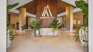 Eine großzügige Lobby mit Holzbalkendecke, großen Kübelpflanzen und einem gut sichtbaren Schild 'Harbor 171'.