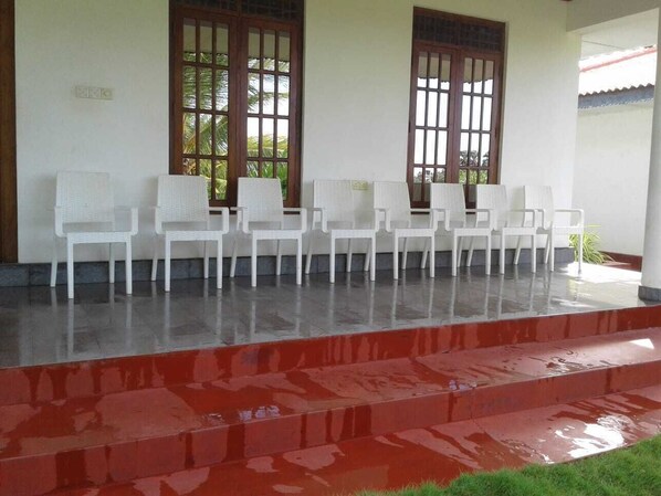 A covered outdoor seating area with white plastic chairs arranged in rows. - Golden Temple Villa  (Trincomalee)
