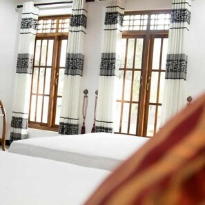 A hotel room with a bed, curtains, and windows. - Golden Temple Villa  (Trincomalee)