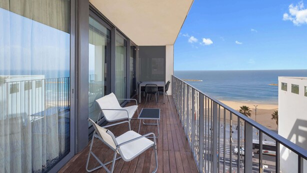 A balcony with a view of the beach, featuring a table and two chairs. - Chic 2BR Apartment w/ Balcony & Sea View by HolyGuest (Tel Aviv-Yafo)