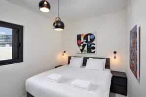 Ein modernes Hotelzimmer mit einem großen Bett, zwei Nachttischen, einem Fenster und einem Wandbild.
