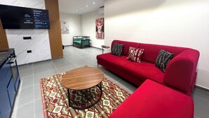 A modern living room with a red sofa, patterned rug, and a wooden coffee table. - The Velvet Nest (Tirana)