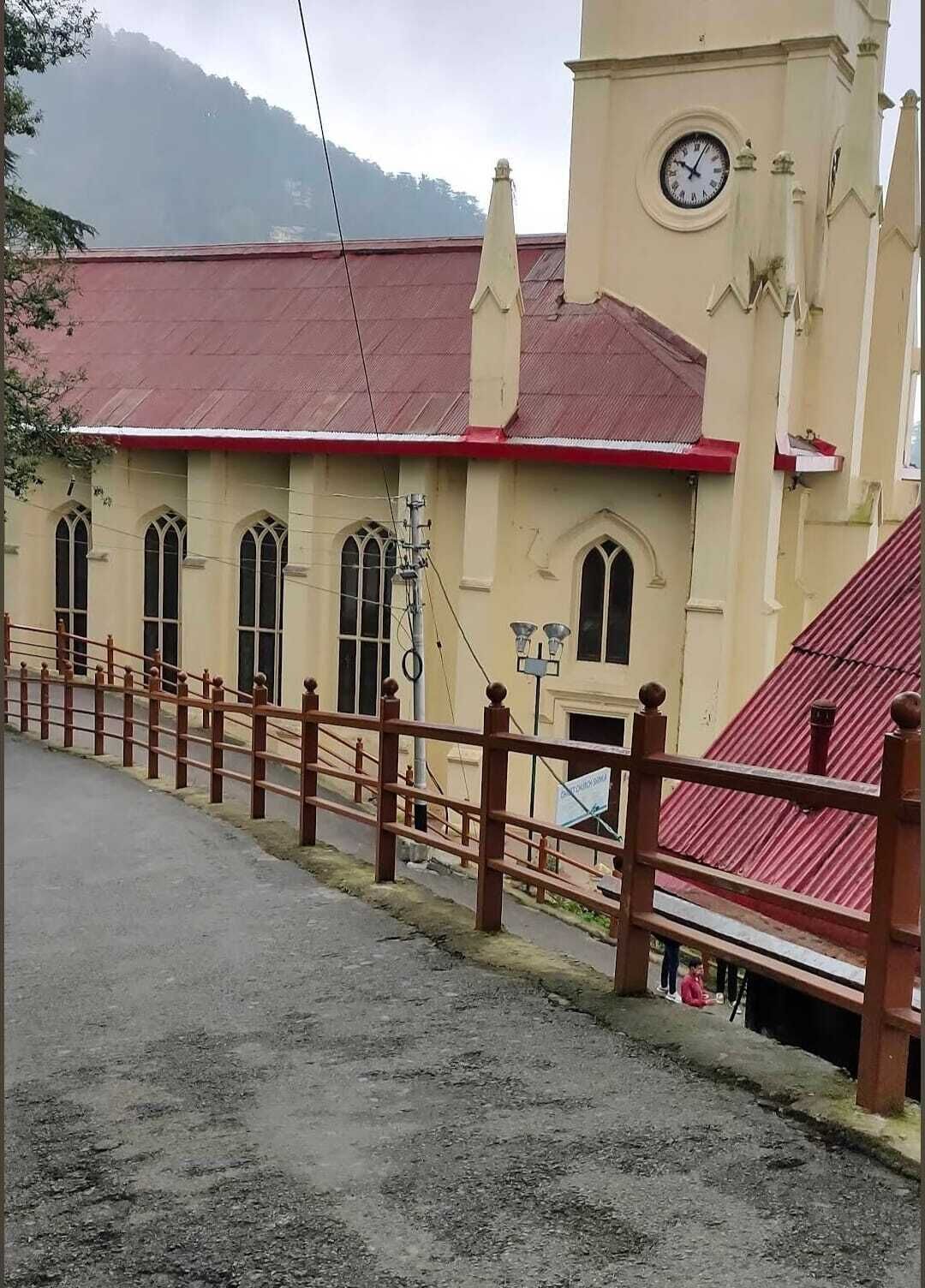 Una iglesia con una torre del reloj, ventanas de arco y techo rojo.