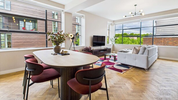 A spacious living area with a large window, a dining table with chairs, a sofa, and a TV. - Spacious and Bright Apartment by Tech City (Greater London)