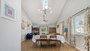 A dining area with a wooden floor, a table set for four, and a ceiling fan.