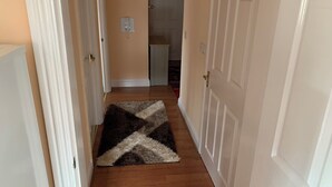 A hallway with wooden flooring, white doors, and a patterned rug.