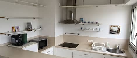 Compact kitchen with modern design, coffee maker, microwave, toaster, sink, and storage.
