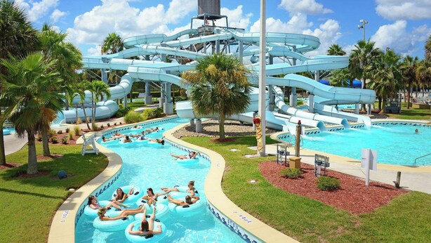 Un parc aquatique doté d’une grande piscine, de nombreux toboggans et de personnes sur des bouées gonflables.