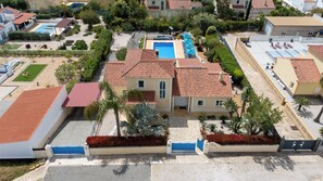 A residential area with a swimming pool, red-tiled roofs, and a gated entrance. - Gorgeous, family home close to Olhão, with distant sea views and a hot tub (Quelfes)