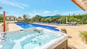 A swimming pool with lounge chairs and umbrellas, a hot tub, and a patio area with outdoor furniture. - Gorgeous, family home close to Olhão, with distant sea views and a hot tub (Quelfes)