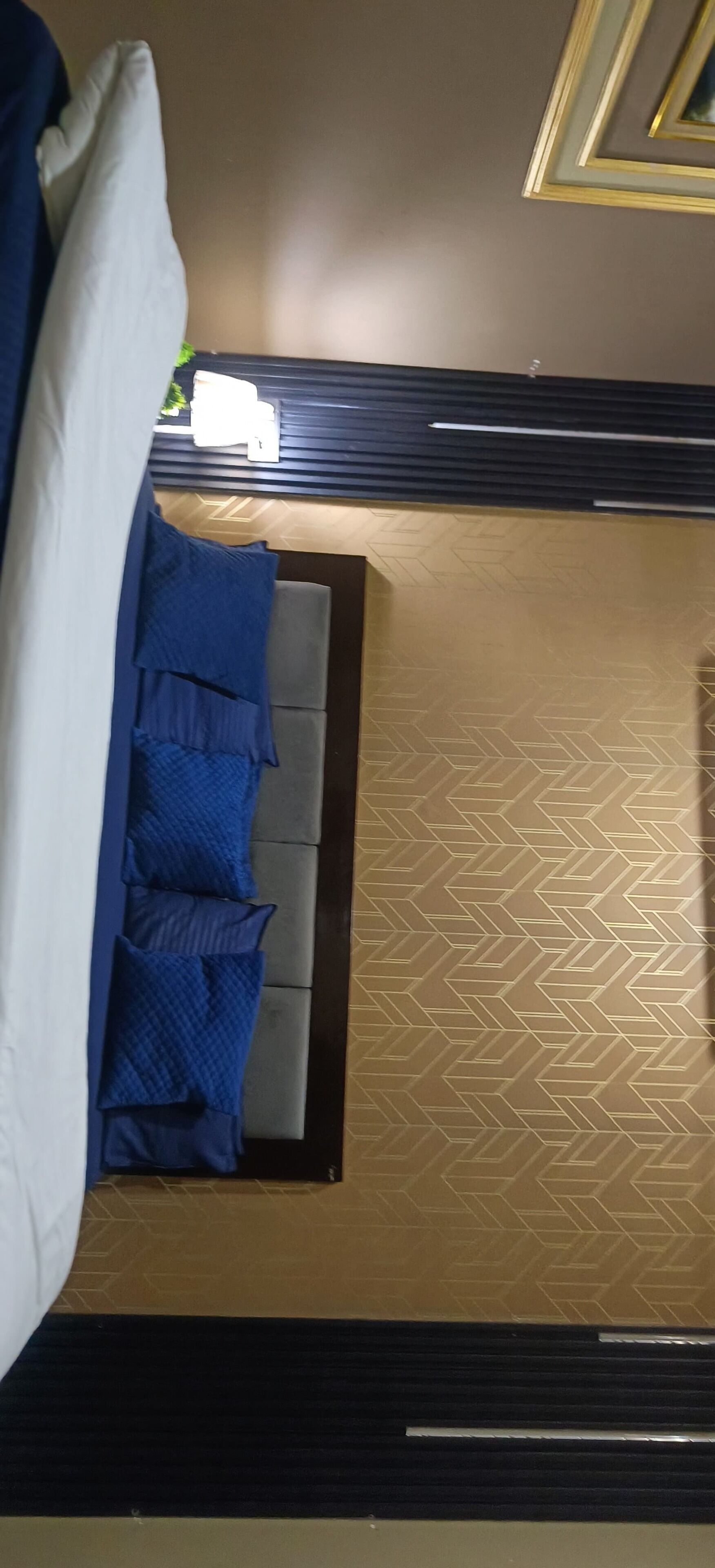 A room with a bed, a grey sofa, and a patterned floor.