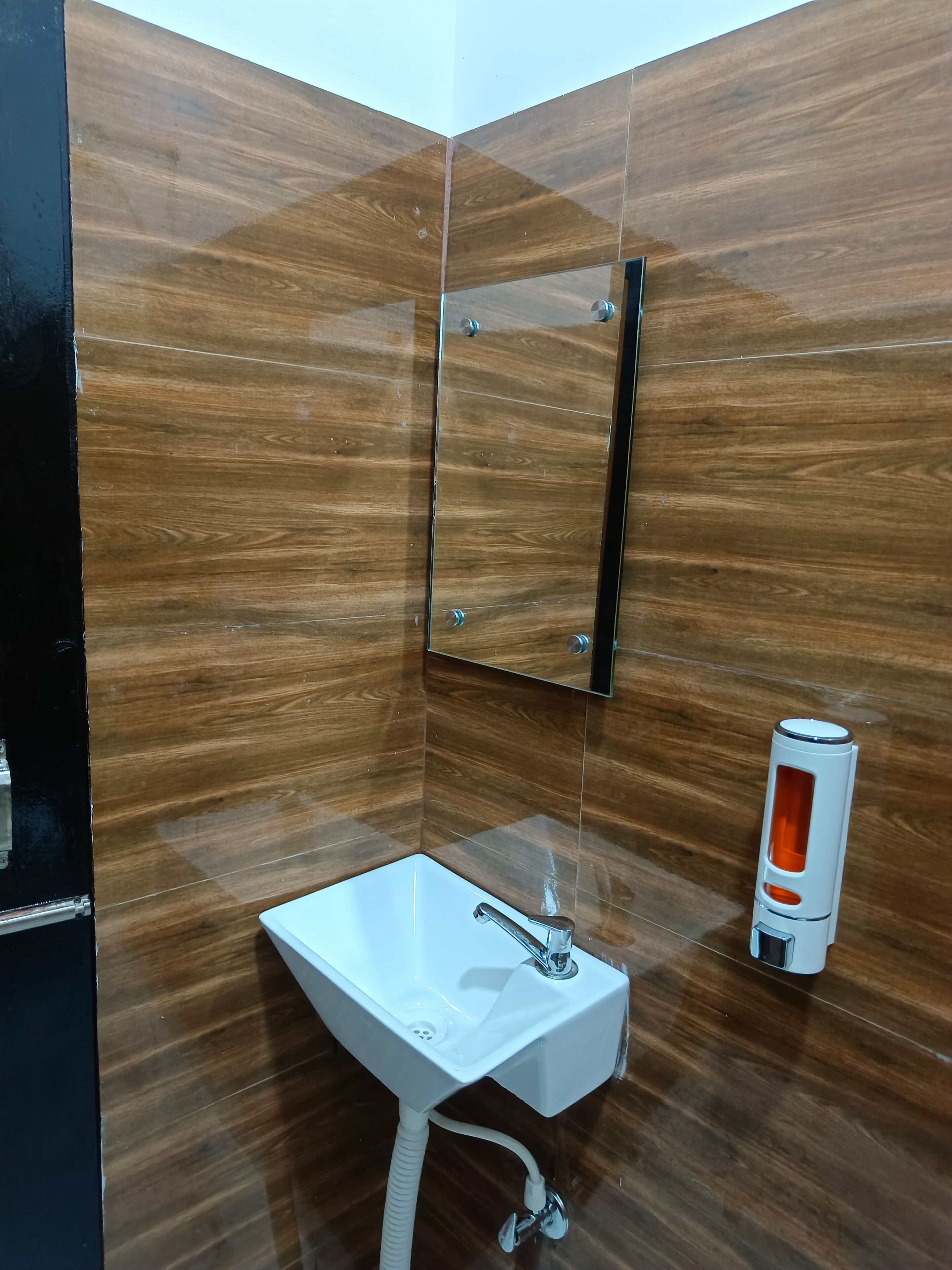 Une salle de bain avec un lavabo blanc, un miroir et un sèche-mains.