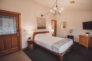 Un dormitorio con cama de madera, lámparas de noche, un candelabro, un televisor y un espejo.