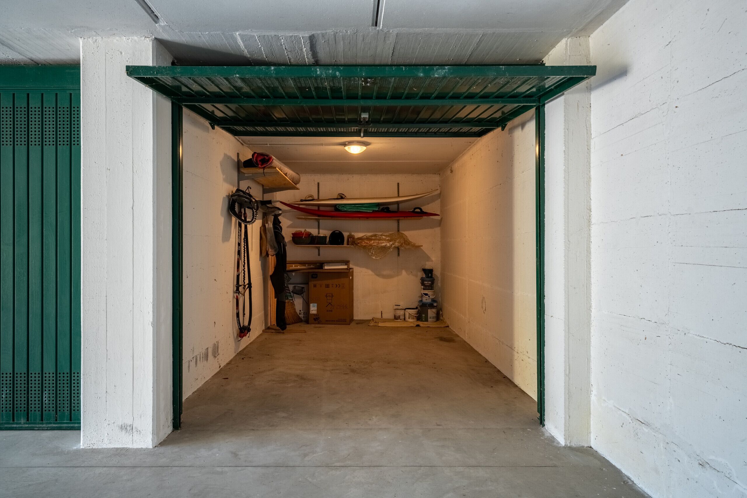 A narrow hallway with a green door on the left, a ceiling fan, and a surfboard rack on the right.