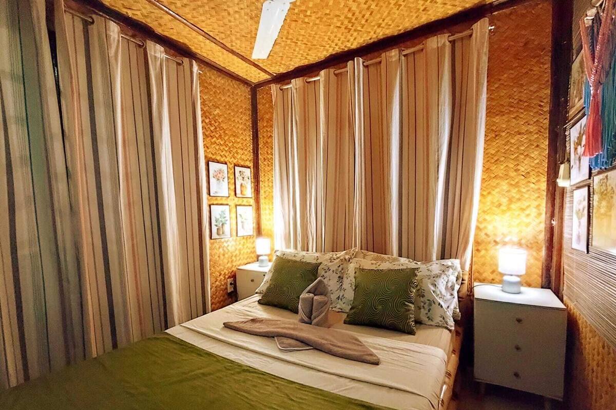 A room with a bed, two nightstands, a lamp on each, and a woven ceiling.