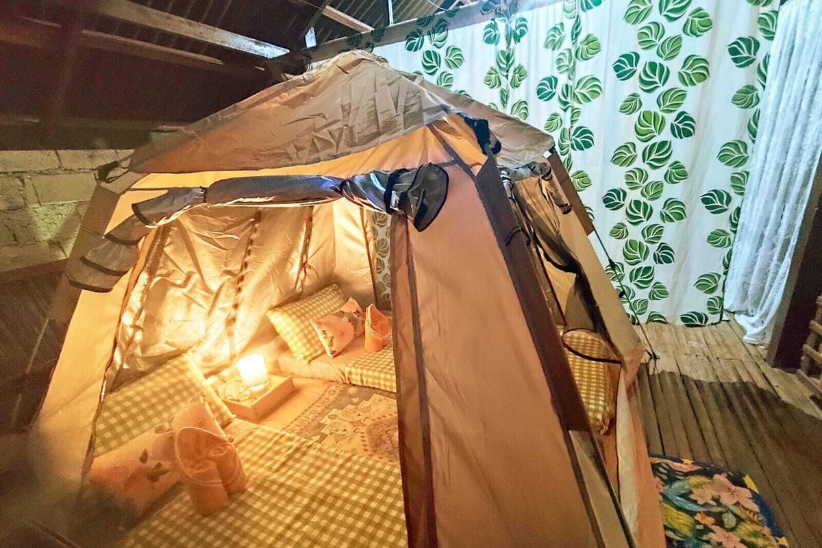 A tent with a checkered floor, a small table, and a candle.