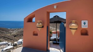A view of a building with a door leading to a covered outdoor area, a sign with a heart symbol, and a view of the sea. - Amphora Aelia Gem - Akrotiri Seaview Getaway (Akrotiri)