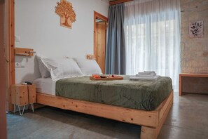 Ein hölzernes Bett mit einer grünen Decke, ein Nachttisch, ein Fenster mit Vorhängen.